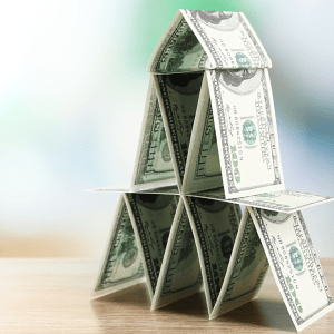 A pyramid composed of one hundred dollar bills on a wooden desk