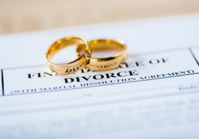 Two broken golden wedding rings on a divorce decree