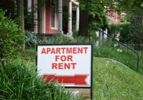 Apartment for rent sign displayed on residential street.