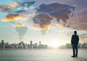 International business concept with businessman on city skyline background with network on map and sunlight