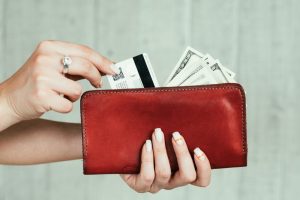 wealth and finances. money earning. cash and credit cards. welfare and income concept. woman hands holding a red leather wallet full of currency.