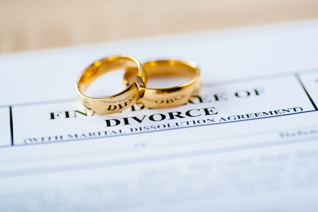 Two broken golden wedding rings on a divorce decree