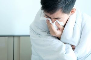 Sick man is flu, using a paper napkin and he have a runny nose. And he was covered in warm cloth.Health concept