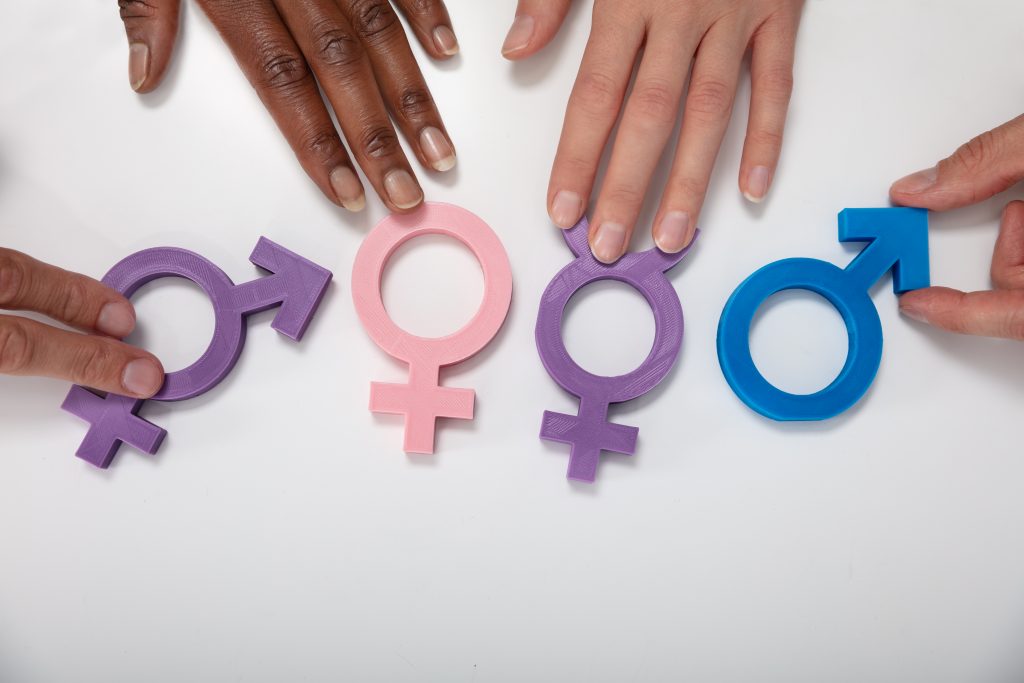 An Overhead View Of Multiethnic People Holding Different Type Of Gender Sign On White Table