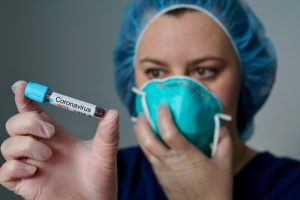 nurse holding vile of coronavirus in her hand
