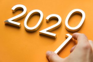 Close-up of metal numbers 2021 and hand on orange background. change year 2020 to 2021