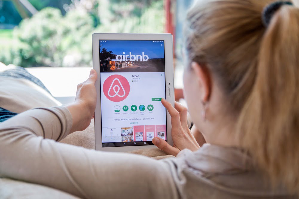 Airbnb on womans ipad making reservations in living room