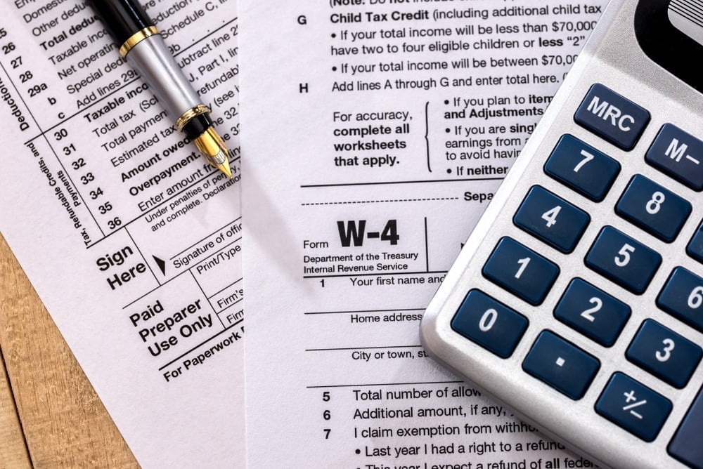 Close up image of a W-4 tax form and a calculator.